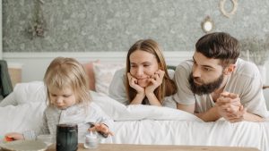 A loving family of three enjoying time together in a peaceful bedroom setting.